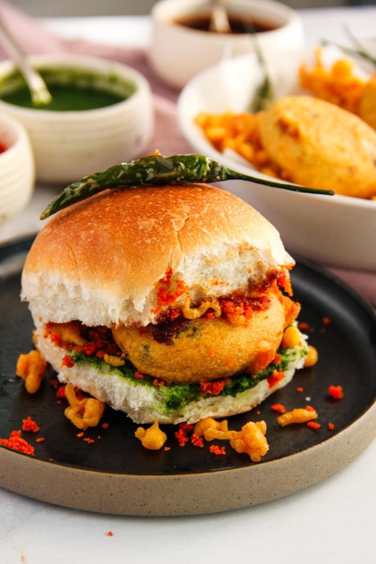 vada pav in a black plate with green fried chili (1)